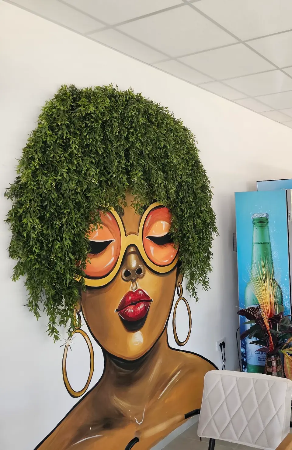 Mural of a woman with hair made of greenery and round coral-tinted glasses, inside Pozitiva Bar