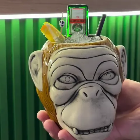 The Drunk Monkey cocktail in a ceramic monkey-head mug, in front of the green bar